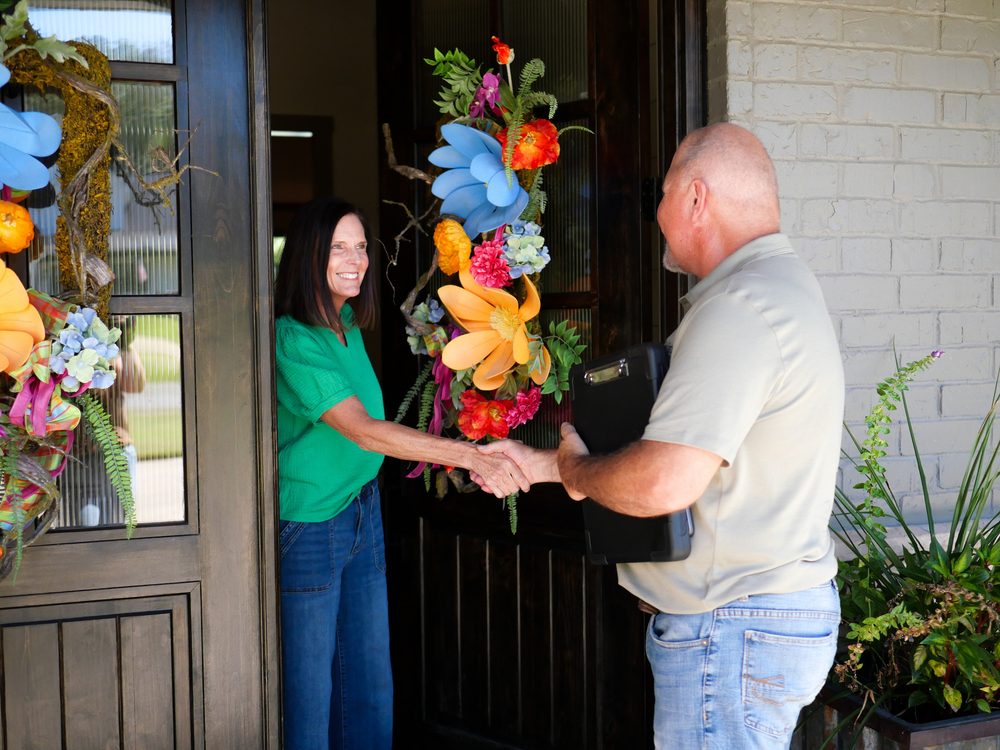 Brett Devine shaking hands with a homeowner at their front door