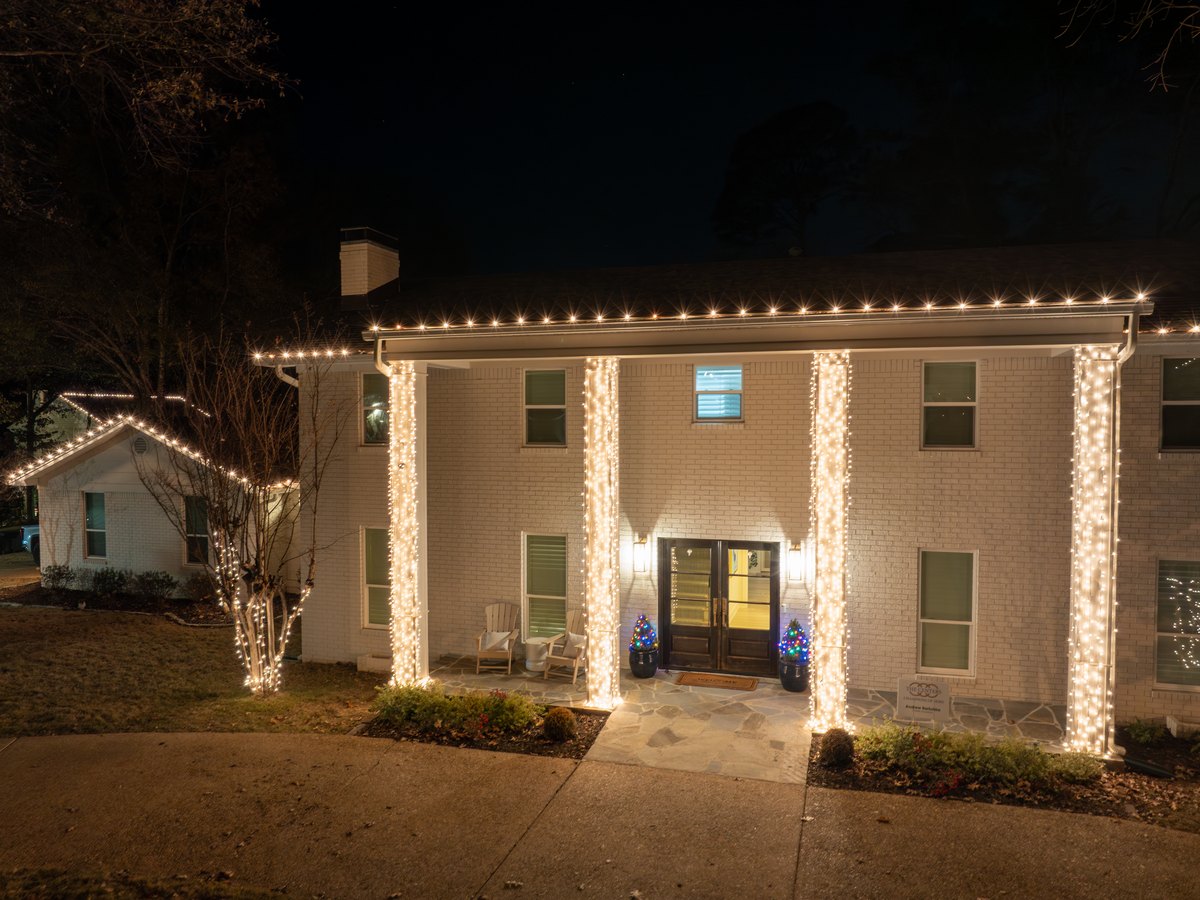 Holiday lighting wrapped around the columns and entry of a two-story home
